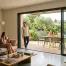 Grande baie vitrée coulissante trois vantaux ouverte sur une terrasse dans un salon moderne