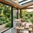 Véranda lumineuse avec grande baie vitrée coulissante en aluminium ouverte sur le jardin