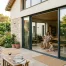 Grande baie vitrée coulissante en aluminium ouverte sur un jardin